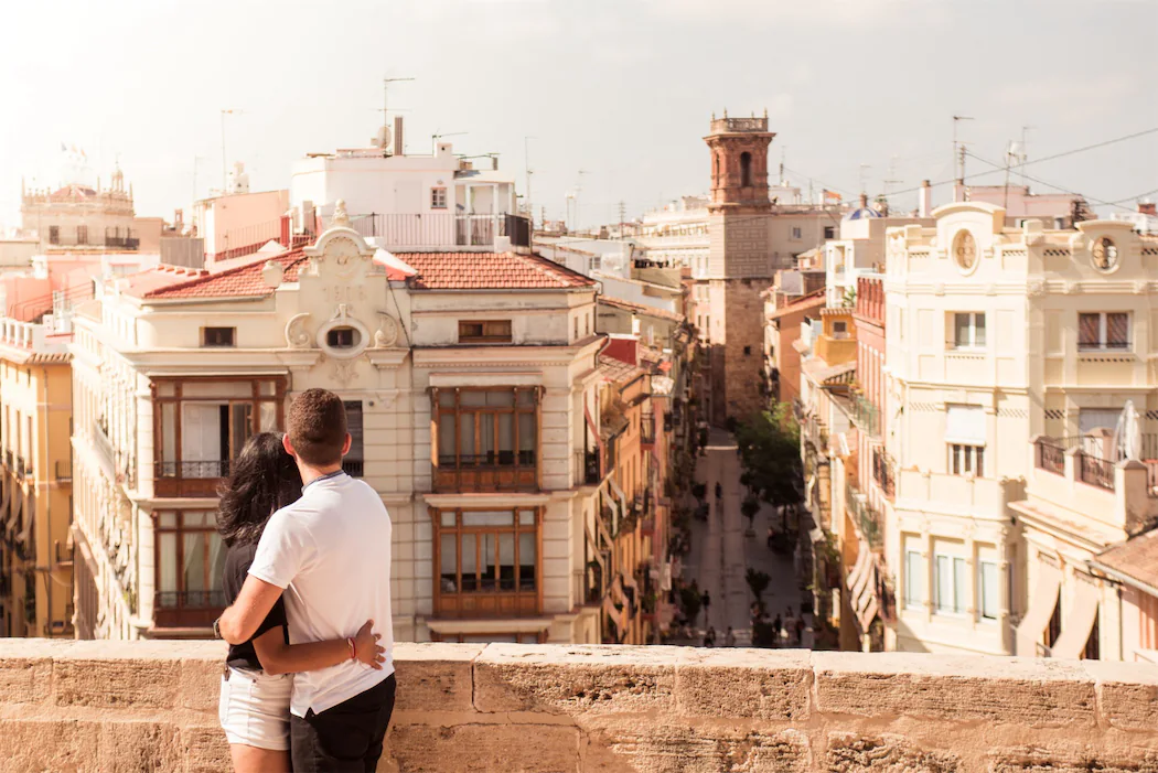 A couple embracing while enjoying a scenic cityscape from a rooftop in Granada, Spain, where spring and autumn offer pleasant weather for city exploration