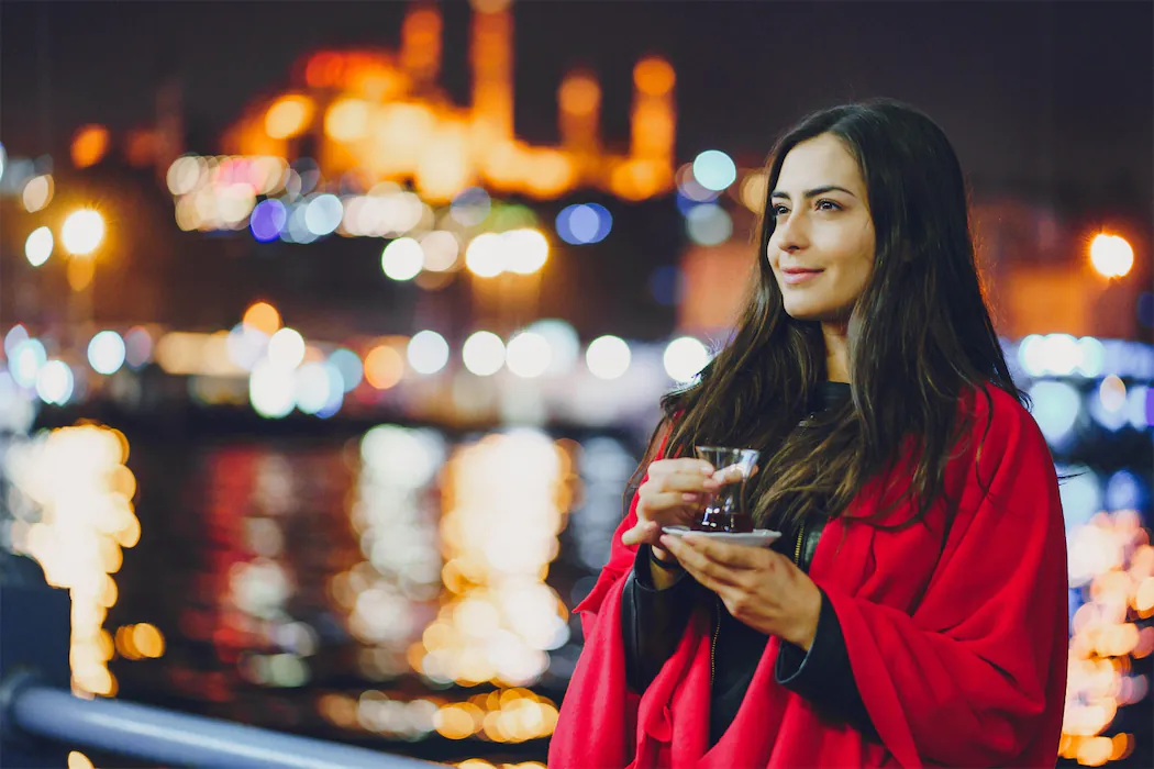 Woman enjoying a serene moment by the waterfront in Porto, taking in the illuminated city skyline during Shin-Tours Luxury Tours. A blend of tranquility and urban energy, perfect for a luxury tour experience in Portugal's cultural hubs