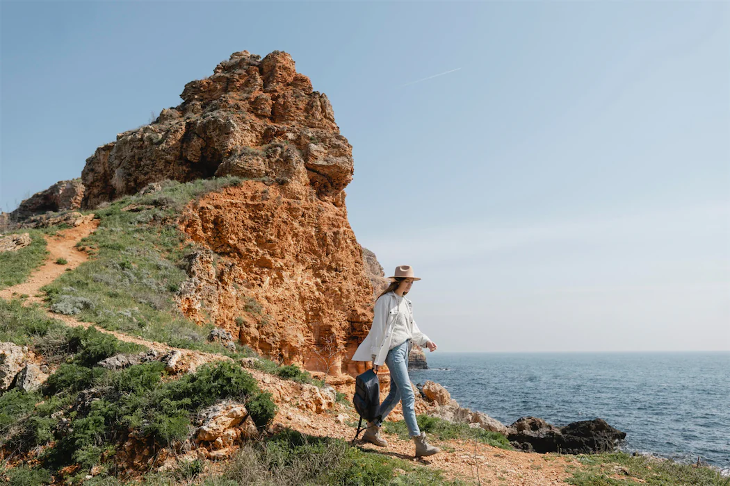 A traveler hikes along the rugged cliffs of the Algarve, enjoying the stunning coastal views on a luxury tour. ShinTours luxury tours offer exclusive experiences in Portugal’s most breathtaking locations, perfect for those seeking adventure and relaxation in nature.