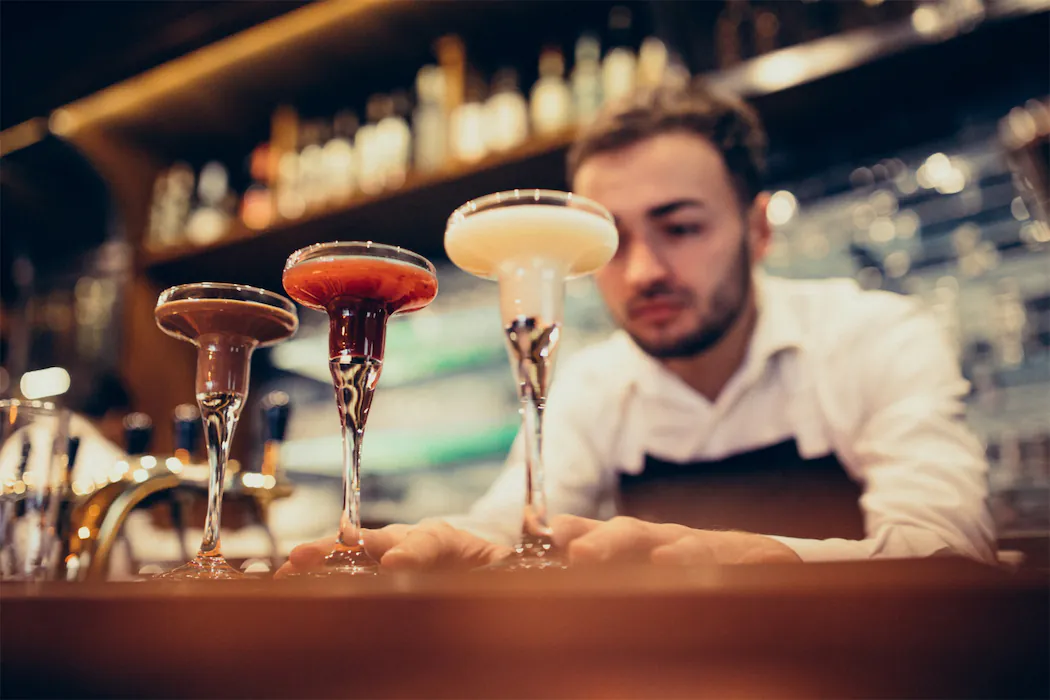  bartender arranging cocktails at Sips, a premier cocktail bar in Barcelona known for its creativity and craftsmanship, featured in Shin-Tours luxury tours.